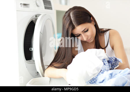 Bild der junge hausfrau mit Wäsche neben Waschmaschine Stockfoto