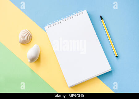 Sommerferien Konzept mit gelben Streifen und Pen, Notepad und Muscheln auf blau-grünen Hintergrund. Stockfoto