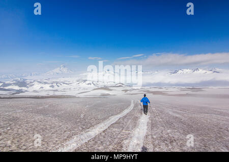 Mann auf schneebedeckten Feld in Kamtschatka Berge in der Nähe von Schnee bedeckten Vulkane Stockfoto