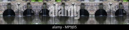 Brunnen mit Wasserfall mit Stein Dekoration im Garten oder Park. Landschaft design Detail. Stockfoto