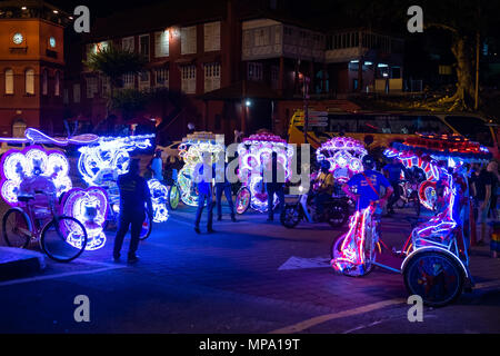 Malakka, Malaysia - 03 Februar 2018: Fahrer von touristischen Tuktuk mit Lichtern und Musik auf night street Stockfoto