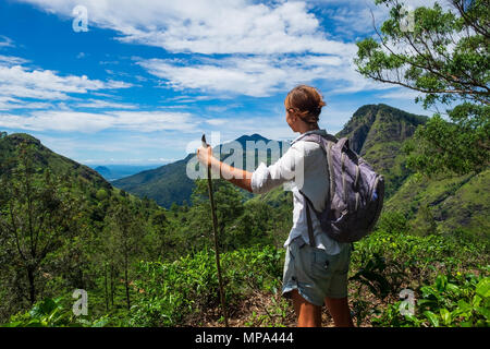 Kaukasische Frau steht zwischen Teebüschen und Blick auf die Berge Stockfoto