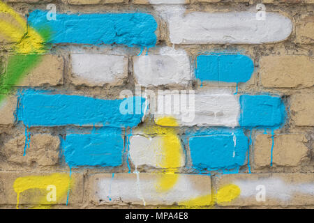 Mehrere bemalte Steine in Blau, Gelb und Weiß auf eine alte schmutzige Mauer, als Graffiti. Bunte grunge Textur der Wand. Abstrakte moderne Hintergrund Stockfoto