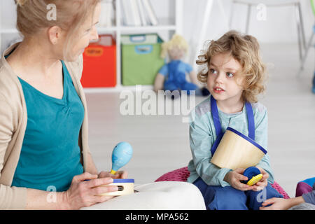 Junge Kindergärtnerin Lehre little boy die Musik zu spielen Stockfoto