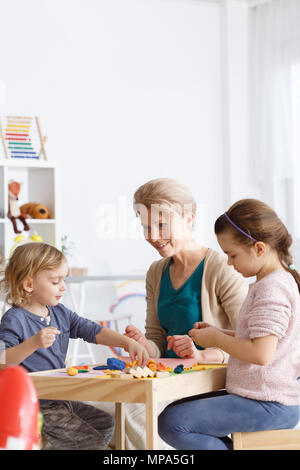 Vorschullehrer und zwei Mädchen, die Spaß an Kunst Klassen im Kindergarten Stockfoto