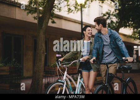 Glücklich der Mann und die Frau zu Fuß auf einer Straße mit ihren Bikes. Junges Paar mit dem Fahrrad über die Straße der Stadt. Stockfoto