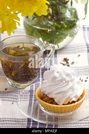 Kräutertee in Glasschale und Blumen auf Holztisch Stockfoto