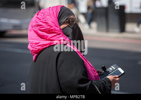 Eine muslimische Frau auf der Oxford Street tragen vivid Pink/rosa Schal. London, Großbritannien. Stockfoto