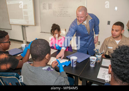 170407-N-GM 597-014 Portsmouth, Virginia (07.04.2017) Hospital Corpsman 3. Klasse Michael Murphy, fragt eine sechste Klasse Student im Park View Volksschule der Name eines Virus auf einem ausmalbilds auszusprechen. Mehr als ein Dutzend Mitarbeiter von Naval Medical Center Portsmouth in Career Day an der Grundschule in Portsmouth mit der Einrichtung von drei Interaktive Wissenschaft, Technologie, Ingenieurwesen und Mathematik (STEM) - Ähnliche Stationen in Science Lab der Schule teilgenommen. Stockfoto