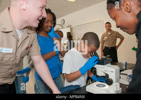 170407-N-GM 597-119 Portsmouth, Virginia (April 7, 2017) eine vierte Klasse Student im Park View Grundschule sieht durch das Mikroskop im Labor Station während Hospital Corpsman 3. Klasse Michael Murphy (links) erklärt, was der Student ist zu sehen. Mehr als ein Dutzend Mitarbeiter von Naval Medical Center Portsmouth in Career Day an der Grundschule in Portsmouth mit der Einrichtung von drei Interaktive Wissenschaft, Technologie, Ingenieurwesen und Mathematik (STEM) - Ähnliche Stationen in Science Lab der Schule teilgenommen. Stockfoto