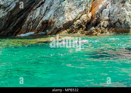 Schnorcheln im kristallklaren Wasser. Menschen Schwimmen im kristallklaren Wasser. Azurblaues Wasser in der Nähe von Felsen auf der Insel von Griechenland. Vater und Kind haben Spaß im Wasser. Stockfoto