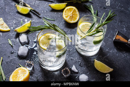 Alkoholisches Getränk Gin Tonic Cocktail mit Zitrone, Rosmarin und Eis auf Tisch aus Stein. Stockfoto