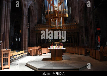 Ein Mitglied des Klerus leuchten Kerzen für die Opfer während der Manchester Arena National Service der Gedenkfeier in der Kathedrale von Manchester zu einem Jahr seit dem Angriff auf Manchester Arena. Stockfoto