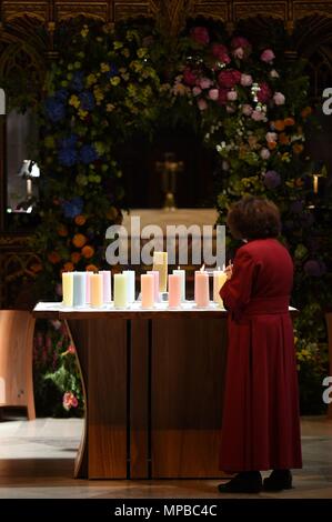 Ein Mitglied des Klerus leuchten Kerzen für die Opfer während der Manchester Arena National Service der Gedenkfeier in der Kathedrale von Manchester zu einem Jahr seit dem Angriff auf Manchester Arena. Stockfoto