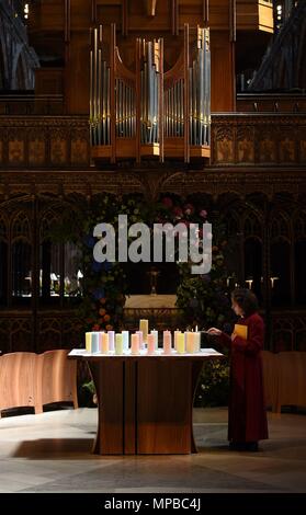 Ein Mitglied des Klerus leuchten Kerzen für die Opfer während der Manchester Arena National Service der Gedenkfeier in der Kathedrale von Manchester zu einem Jahr seit dem Angriff auf Manchester Arena. Stockfoto