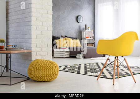 Geräumiges Schlafzimmer mit weißen Wand. Holz Couchtisch und gelben Sesseln. Durch die Mauer grau mit gelben Kissen Stockfoto