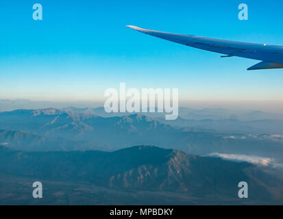 Blick aus dem Flugzeug Fenster fliegen südlich von Santiago, Chile mit Anden Ausläufern und Low und Low level Cloud bei Dämmerung Stockfoto