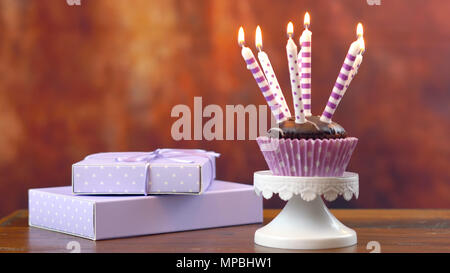 Lila Thema Geburtstag Kuchen mit Kerzen und Geschenke gegen eine rustikale Holz Hintergrund. Stockfoto