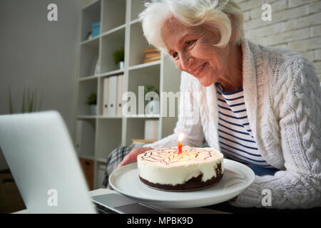 Ältere Frau feiert Geburtstag über Laptop Stockfoto