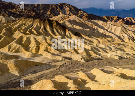 Sonnenaufgang über Mudstone Hügel und Schluchten - eine Nahaufnahme der morgendlichen Sonnenlicht auf Schlamm Stein Hügel und Schluchten am Death Valley National Park, USA Stockfoto