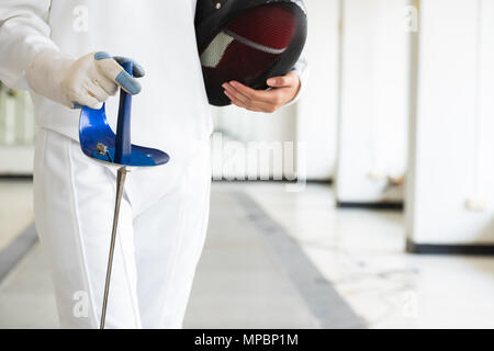 Nahaufnahme eines Fechter in Weiß fechten Anzug und halten ihre Maske und ein Schwert. Sport und Erholung Konzept. Stockfoto