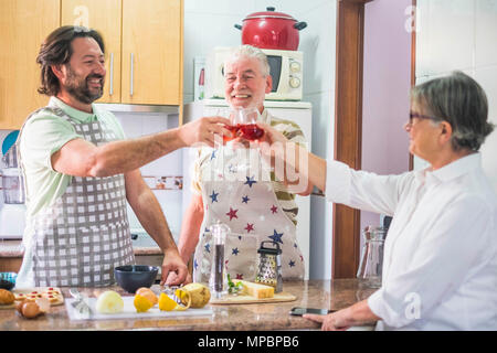 3-köpfige Familie Toasten mit rotem Wein, während der Zubereitung der Speisen in der Küche zu Hause vorbereitet Stockfoto