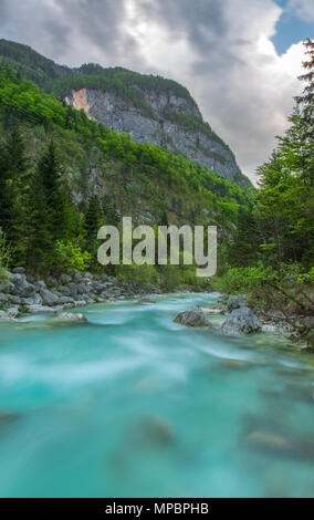 Das türkisfarbene Wasser der Soca - Isonzo Fluss in Slowenien bei der Schneeschmelze. Frühling gekommen ist, üppigen Wälder bedecken die Hänge. Lange Belichtung Bild. Stockfoto