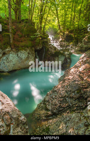 Fluss springt über Felsbrocken mit Türkis, Misty wasser Wasserfälle und Kaskaden in den Wald zu erstellen. Himmlischen Lichts, Sonnenstrahlen im Hintergrund. Stockfoto
