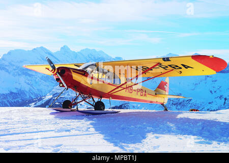 Maennlichen, Schweiz - 31.12.2013: Gelb Flugzeug in die Berge Alpen Gipfel, Maennlichen im Winter Schweiz Stockfoto