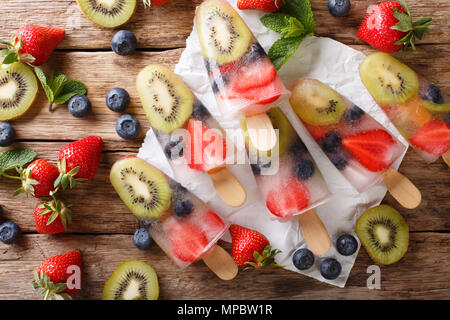 Erfrischende Frucht popsicle am Stiel mit Beeren, Früchten Pfefferminz auf hölzernen Hintergrund Makro. horizontal oben Ansicht von oben Stockfoto