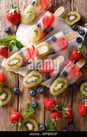 Erfrischende Frucht popsicle am Stiel mit Beeren, Früchten Pfefferminz auf hölzernen Hintergrund Makro. Vertikal oben Ansicht von oben Stockfoto