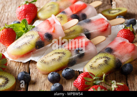 Erfrischende Frucht popsicle am Stiel mit Beeren, Früchten Pfefferminz auf hölzernen Hintergrund Makro. Horizontale Stockfoto