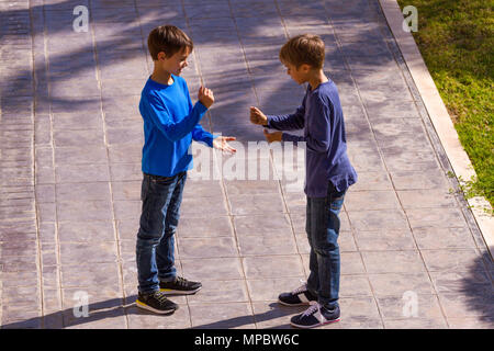 Zwei Jungen spielen Rock Paper Scissors Spiel im Freien Stockfoto