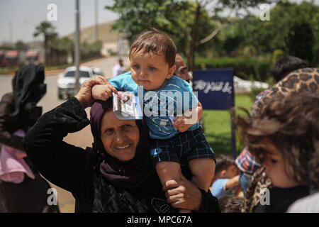 Idlib, Syrien. 22. Mai, 2018. Eine syrische Flüchtlinge in der Türkei lebende Frau trägt ein Kind, bevor es zurück nach Syrien, um die muslimischen Feiertag des Eid al-Fitr zu verbringen, bei Bab al-Hawa Grenzübergang an der Grenze in Syrian-Turkish Idlib, Syrien, 22. Mai 2018. Credit: Anas Alkharboutli/dpa/Alamy leben Nachrichten Stockfoto