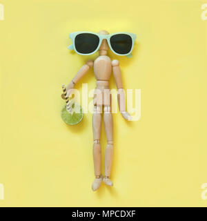 Konzept Hitze im Sommer. Puppe mit frischen Limonen Getränk lag auf gelb wie auf Sand bearch. Uv-Schutz für die Augen und den Körper. Ansicht von oben. Stockfoto