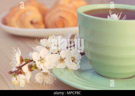 Tasse Kaffee und Croissants in der Nähe von blühenden Zweigen. Toning Stockfoto