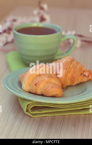 Tasse Kaffee und Croissants in der Nähe von blühenden Zweigen. Toning Stockfoto