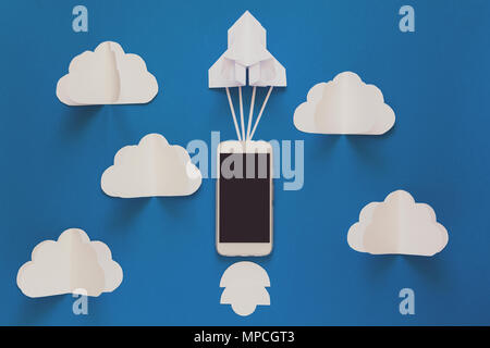 Starten oder schnelle Verbindung Konzept. Die Einführung Papier Rakete mit Smart Phone auf blauen Himmel mit Wolken. Origami. Papier schneiden. Ansicht von oben. Getönt Stockfoto
