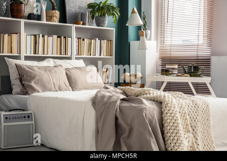 Kreative Nutzung von kleinen Raum in ein stilvolles Schlafzimmer Innenraum mit Designer Einrichtung und gemütliche weiß und beige Bettwäsche Stockfoto