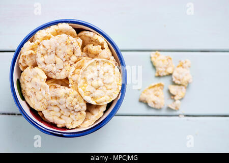 Hohe Betrachtungswinkel und einer Schüssel mit einigen gepuffter Mais und Quinoa Kuchen, auf einem hellgrünen Holztisch Stockfoto