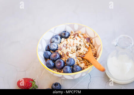 Schüssel Müsli mit Heidelbeeren Früchte, gesundes Frühstück mit Haferflocken, Milch und Obst Stockfoto