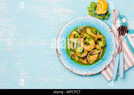 Mexikanische Küche. Aguachile de Camaron. Garnelen aguachile. Garnelen eviche cebiche mit Gurke, Zitrone und violette Zwiebel. Ansicht von oben, blauen Hintergrund. Stockfoto