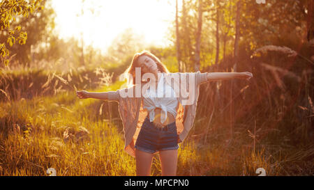 Glückliche junge Frau genießt einen wunderschönen Abend. Warmes Wetter, Sommer, Feld. Stehend mit umarmte Arme Stockfoto