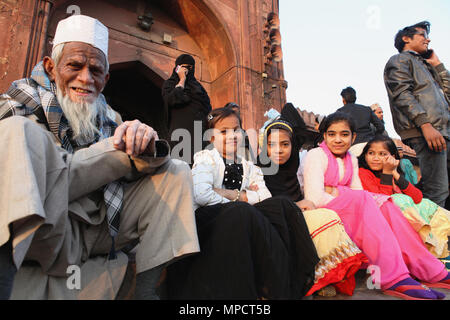 Indien, Neu-Delhi, muslimischen Mädchen und ihren Großvater sitzen auf der Treppe vor dem Eingang der Jama Masjid in der Altstadt von Delhi. Stockfoto