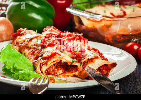 Traditionellen mexikanischen Enchiladas mit Hähnchenfleisch, würziger Tomatensoße und Käse auf dem Teller. Mexikanische Küche. Stockfoto