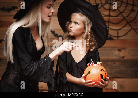 Halloween Konzept - Schöne kaukasischen Mutter spielt mit ihrer kleinen Tochter genießen mit Halloween Süßigkeiten und süße über Fledermäuse und Spinnennetz auf Holz- studio Hintergrund. Stockfoto