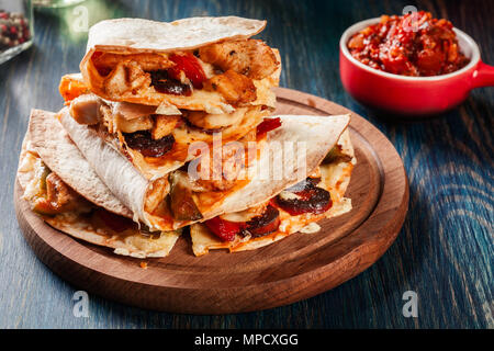 Stapel von Quesadillas mit Hähnchen, Würstchen Chorizo und rote Paprika mit Salsa serviert. Mexikanische Küche. Seitenansicht Stockfoto