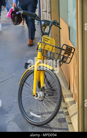 Gelbe dockless Fahrrad links außerhalb eines Gebäudes in einer Stadt Umgebung Stockfoto