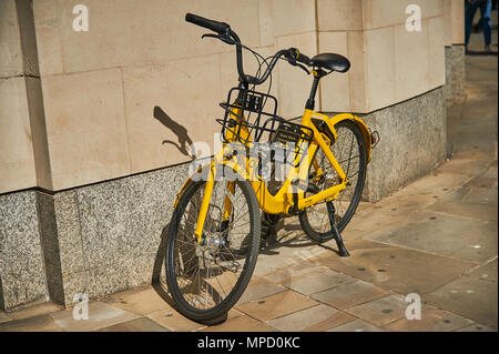 Gelbe dockless Fahrrad links außerhalb eines Gebäudes in einer Stadt Umgebung Stockfoto