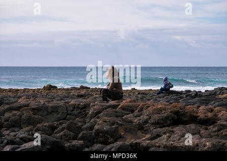 Eine Frau und ein Mann sitzen auf die Kraft des Ozeans auf der Suche während der kalten Jahreszeit wie Winter Stockfoto